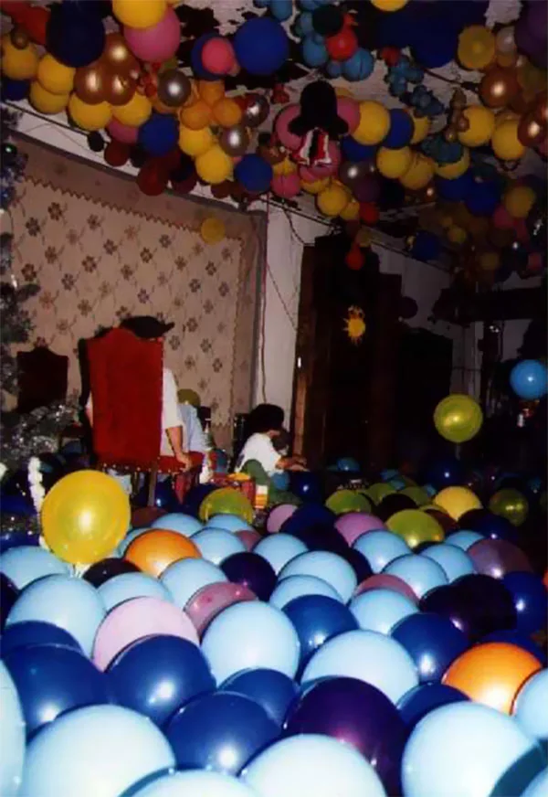 A room filling up with balloons before a party, hundreds of them across the floor and the ceiling.