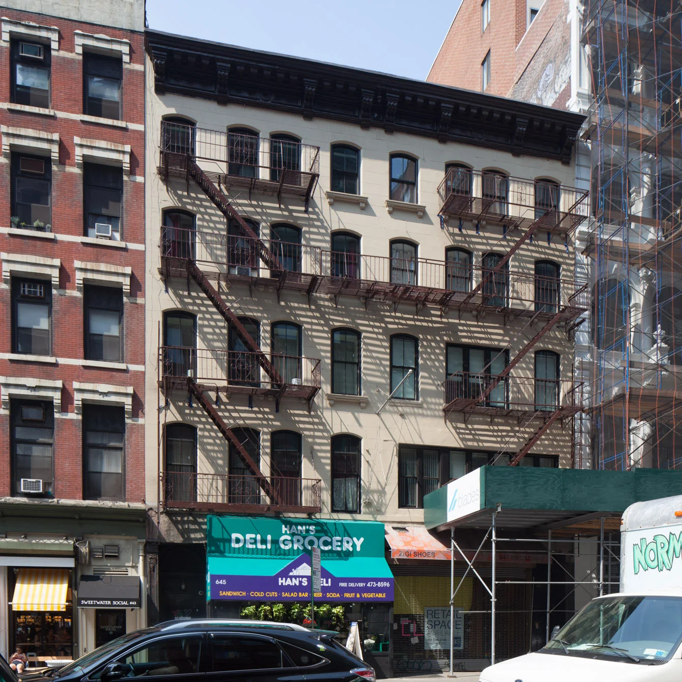 647 Broadway today: a six-storey brick building with fire escapes above a corner deli.