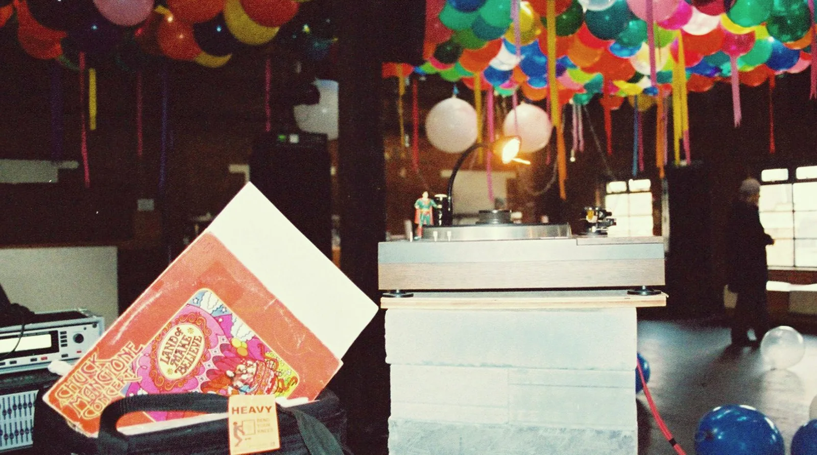 Records leaning against a table in front of the booth at a London Loft party, balloons and paper lanterns overhead.