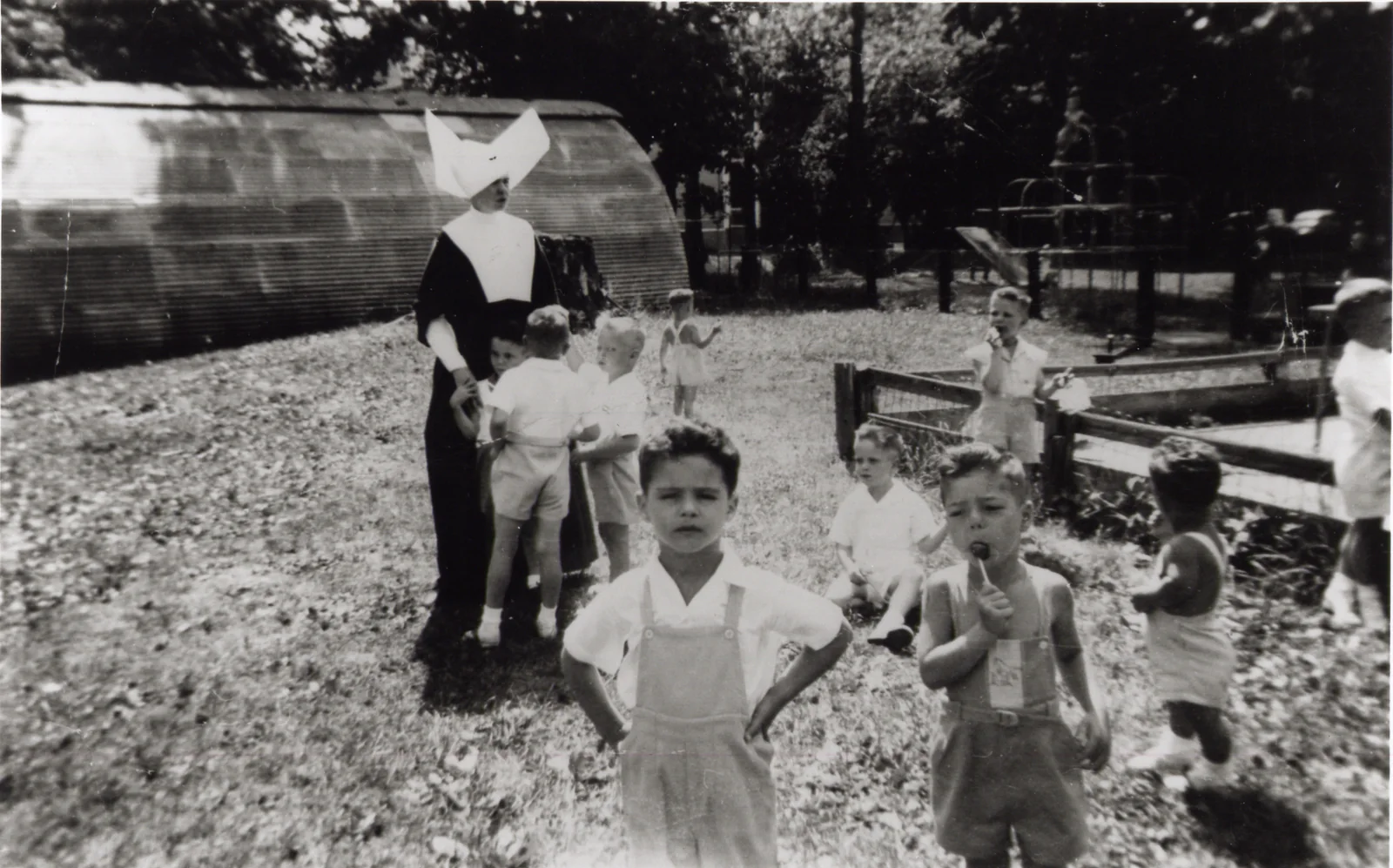 Black-and-white photograph at the children's home in Utica: small boys in a garden, David Mancuso among them, with a nun in a white cornette standing behind.